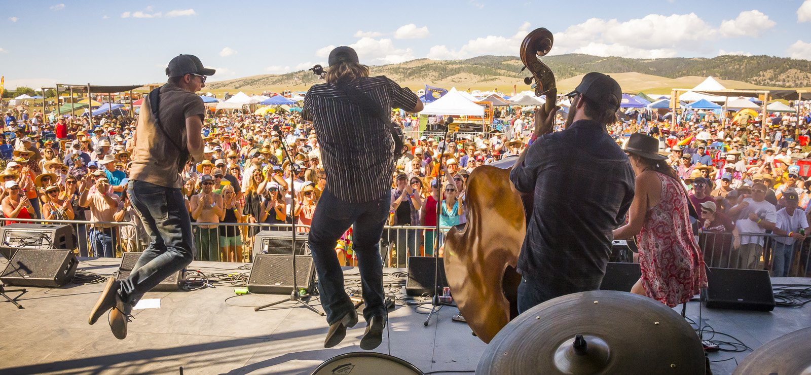 Laney Lou and the Bird Dogs play onstage at Red Ants Pants with a huge crowd in front of them below a blue sky.