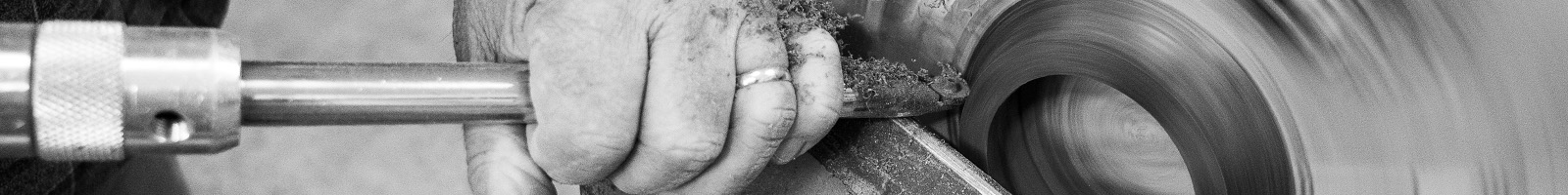 Black-and-white image of Terry Hill's hands holding chisel to bowl he's turning on lathe